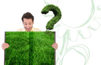 Man holding an open book with a picture of lush lawn.